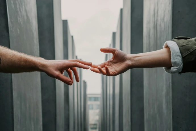 two hands reaching between concrete pillars